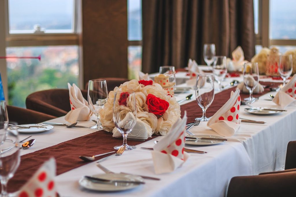 table-with-dishes-near-windows-2487438 Elegant dining table with floral centerpiece and polka-dot napkins at a Kampala restaurant.